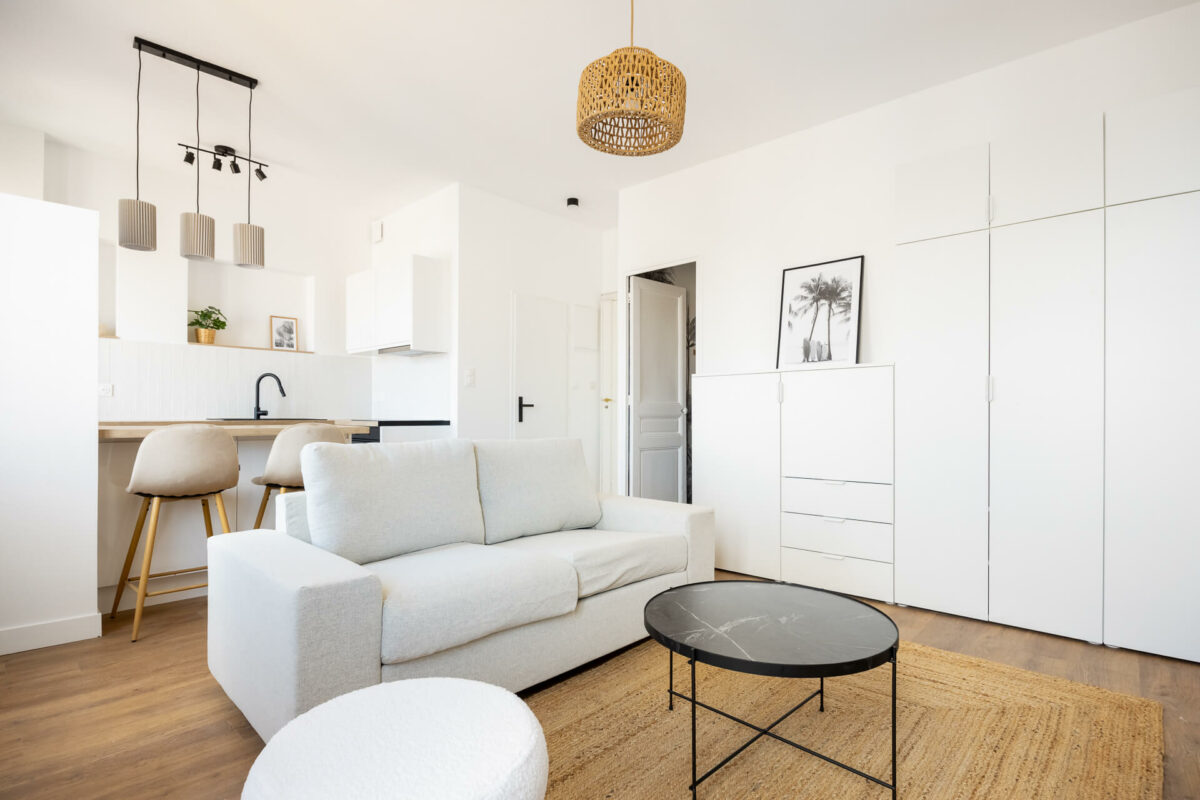 salon rénové lumineux avec canapé beige et cuisine ouverte dans un appartement de 34m2 à Marseille